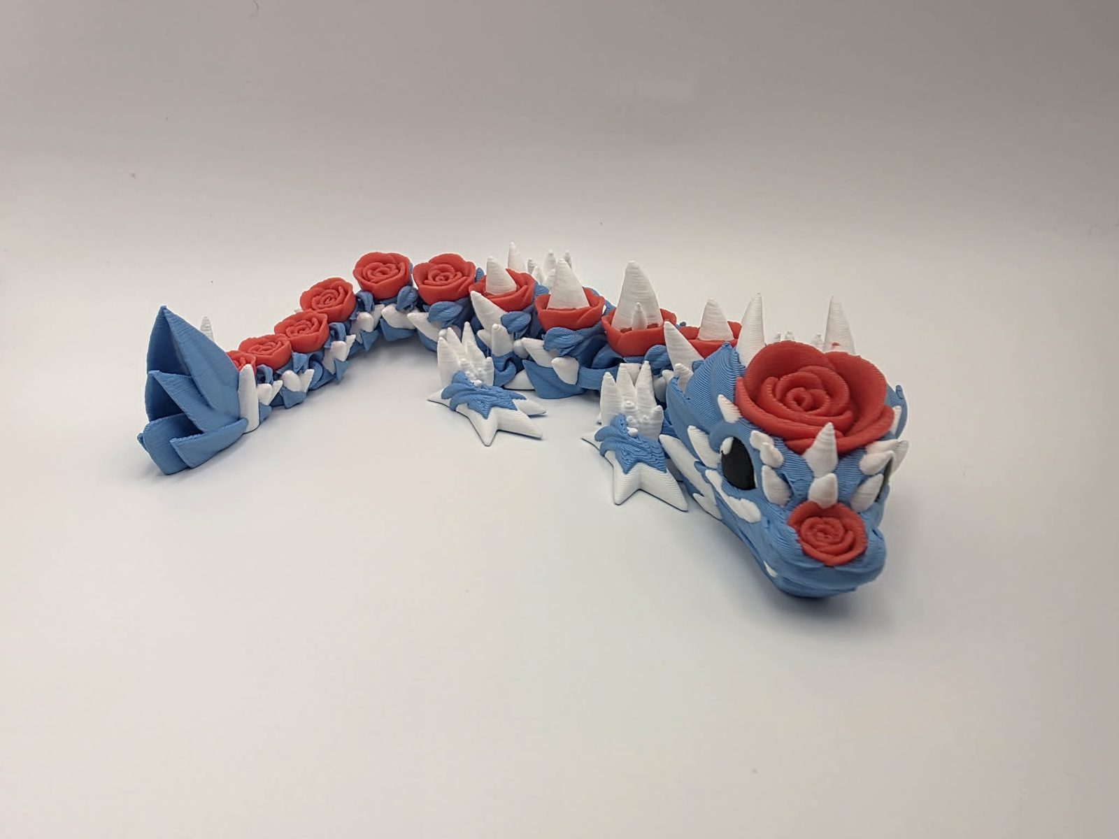 Rose Dragon - Sky Rose Dragon - 10" Long x 3" Wide Outer Foot to Outer Foot x 1.5" Tall - Sky Blue, White, Cherry Red, Black 3D printed item image