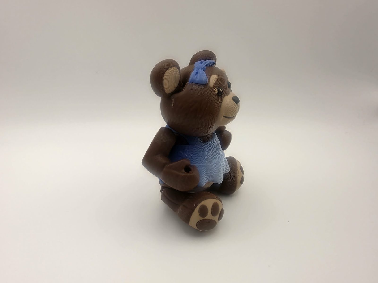 Teddy Bear - Miss Snuggleton - 3" Wide Outer Arm to Outer Arm x 1.4" Belly to Back x 4.25" Head to Feet - Chocolate, Matte Light Brown, Black, Blue and White 3D printed item image